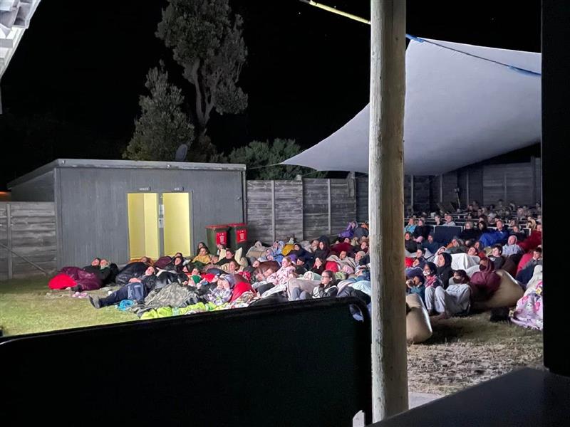 people watching a movie at an outdoor cinema